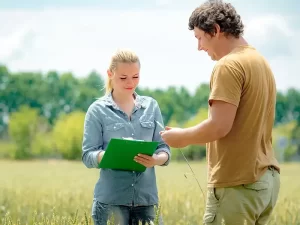 woman with clipboard taking notes with man holding wheat